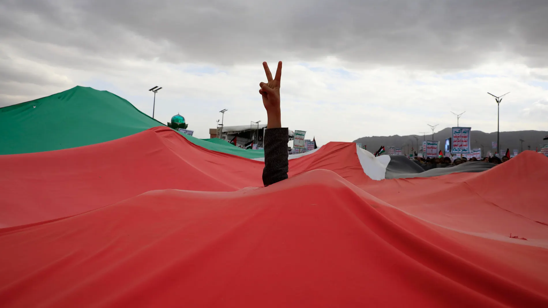 -FOTODELDÍA- Sana'a (Yemen), 16/02/2024.- Un partidario de los hutíes muestra un signo de victoria a través de una bandera palestina durante una protesta contra la designación estadounidense de los hutíes como grupo terrorista, en Saná, Yemen, el 16 de febrero de 2024. Miles de partidarios de los hutíes se manifestaron en Saná para protestar contra la designación estadounidense de los hutíes de Yemen como "grupo terrorista global especialmente designado" que entró en vigor el 16 de febrero, d...