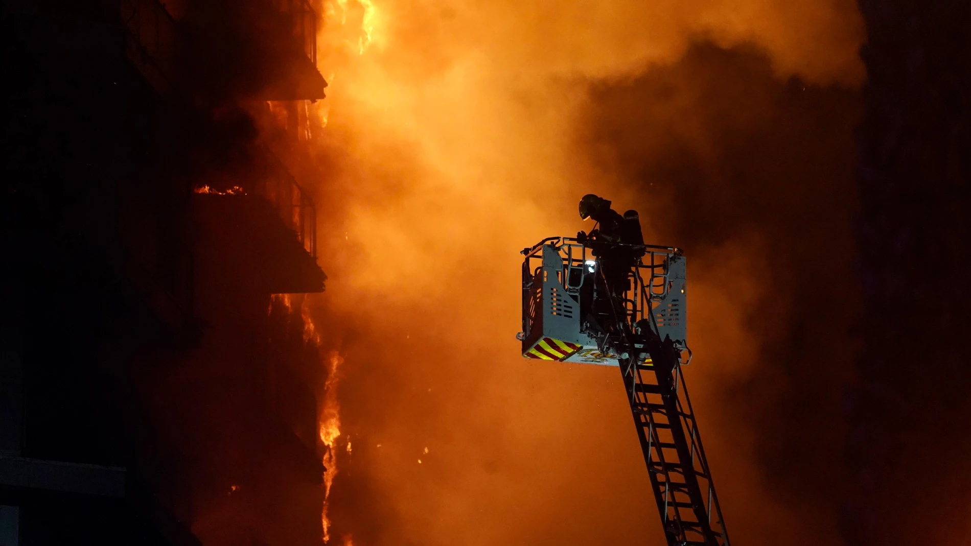 Un bombero trata de apagar el edificio en llamas, en el barrio de Campanar, a 22 de febrero de 2024, en Valencia, Comunidad Valenciana (España). Un incendio de grandes dimensiones ha arrasado un edificio de 14 plantas en el barrio valenciano de Campanar. El fuego, originado en el cuarto piso del inmueble, ha generado una gran columna de llamas y una densa humareda que ha afectado a varias plantas del edificio. El 112 ha movilizado diez dotaciones de bomberos, dos SAMU y un SVB hasta el lugar ...