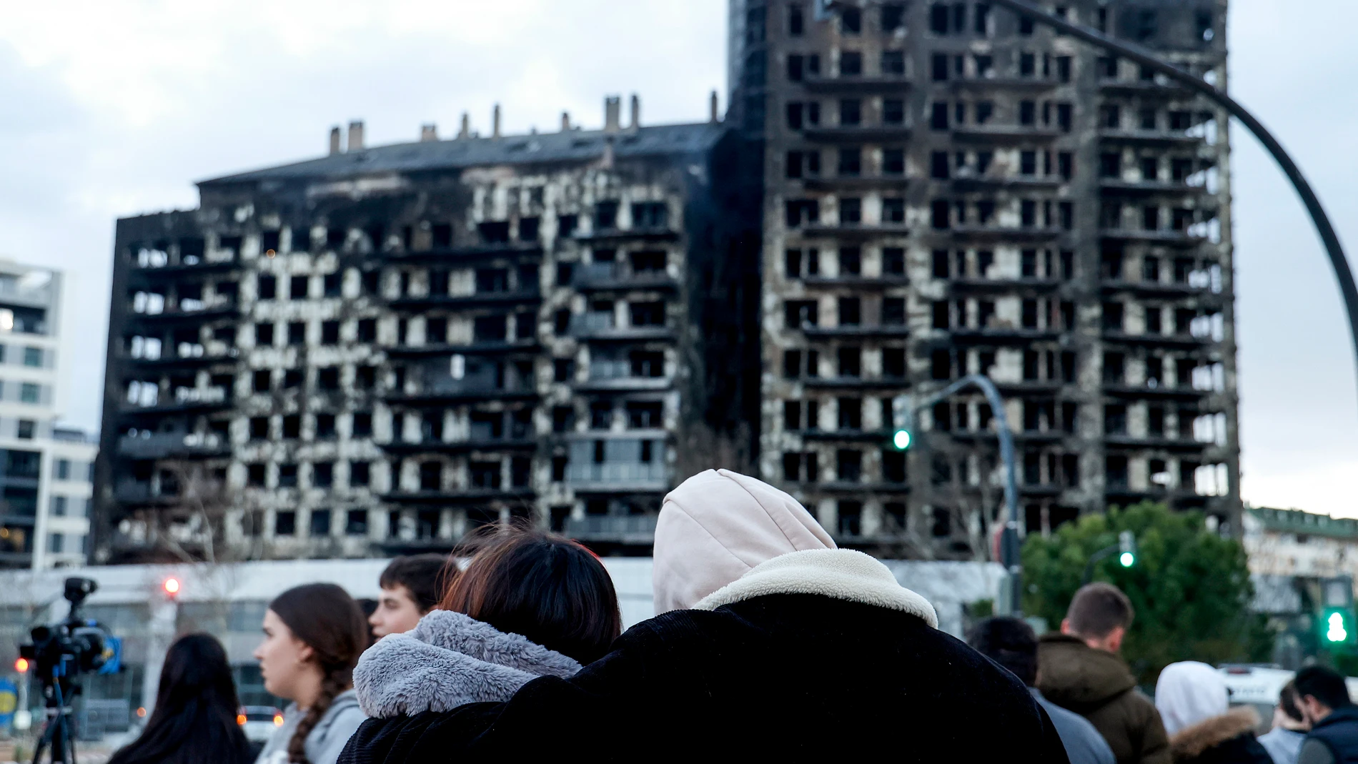 GRAFCVA8604. VALENCIA, 23/02/2024.- Una pareja observa abrazados el edificio incendiado en el barrio de Campanar de València. La cifra de víctimas mortales en el incendio se eleva a 10 tras la primera inspección ocular que han hecho en el interior de las instalaciones los bomberos y la Policía Científica. EFE/Miguel Ángel Polo