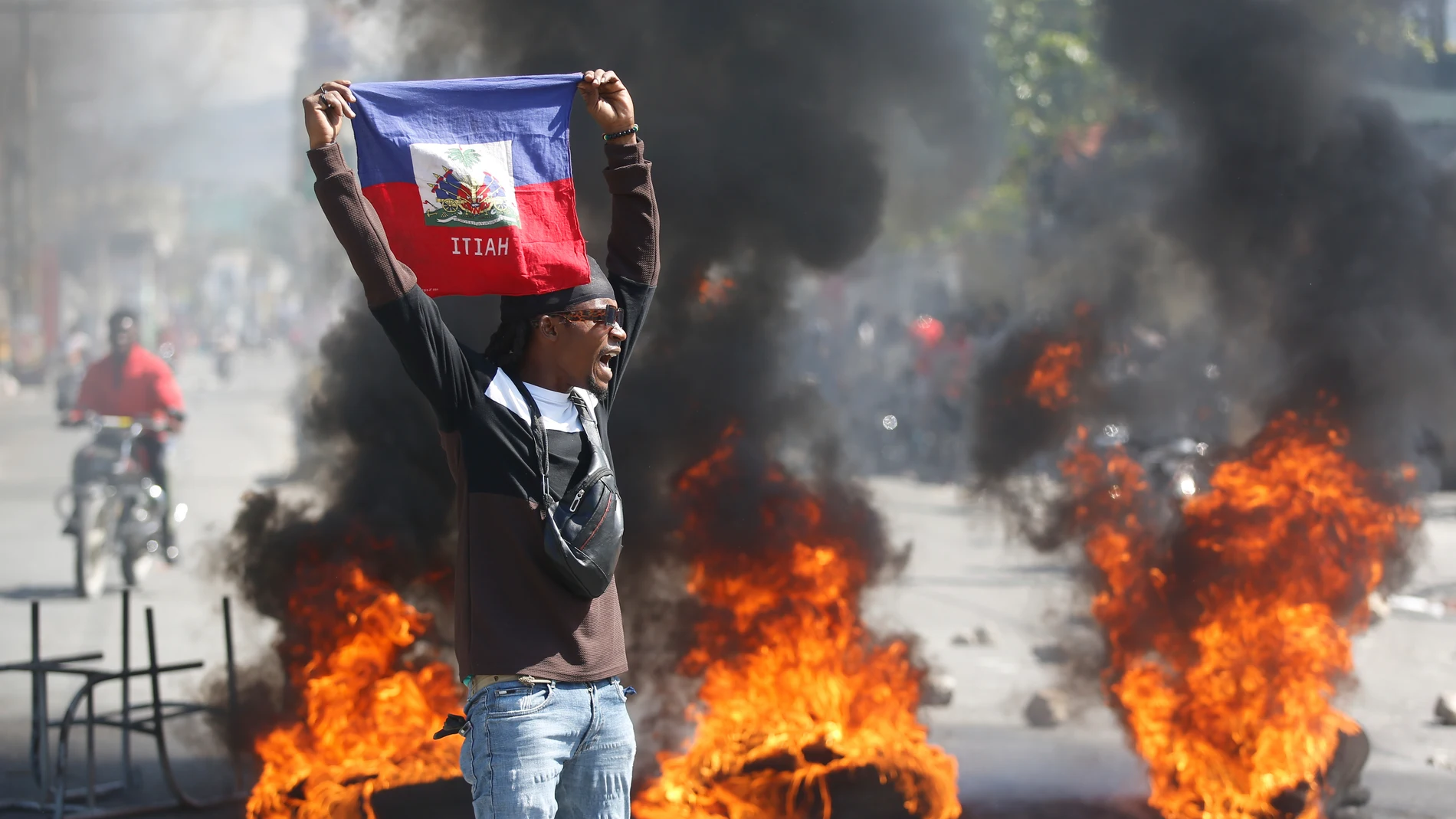 A demonstrator holds up an Haitian flag during protests demanding the resignation of Prime Minister Ariel Henry in Port-au-Prince, Haiti, Friday, March 1, 2024. (AP Photo/Odelyn Joseph)