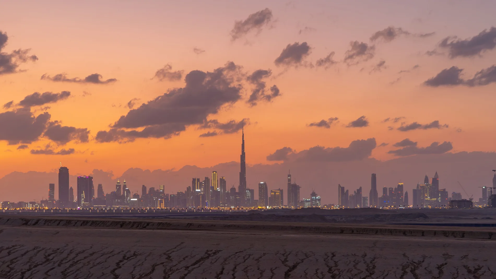 Dubai Downtown skyline with desert sand, United Arab Emirates or UAE. Financial district and business area in smart urban city. Skyscraper and high-rise buildings at sunset.