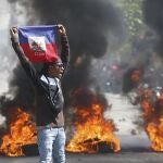 A demonstrator holds up an Haitian flag during protests demanding the resignation of Prime Minister Ariel Henry in Port-au-Prince, Haiti, Friday, March 1, 2024. 