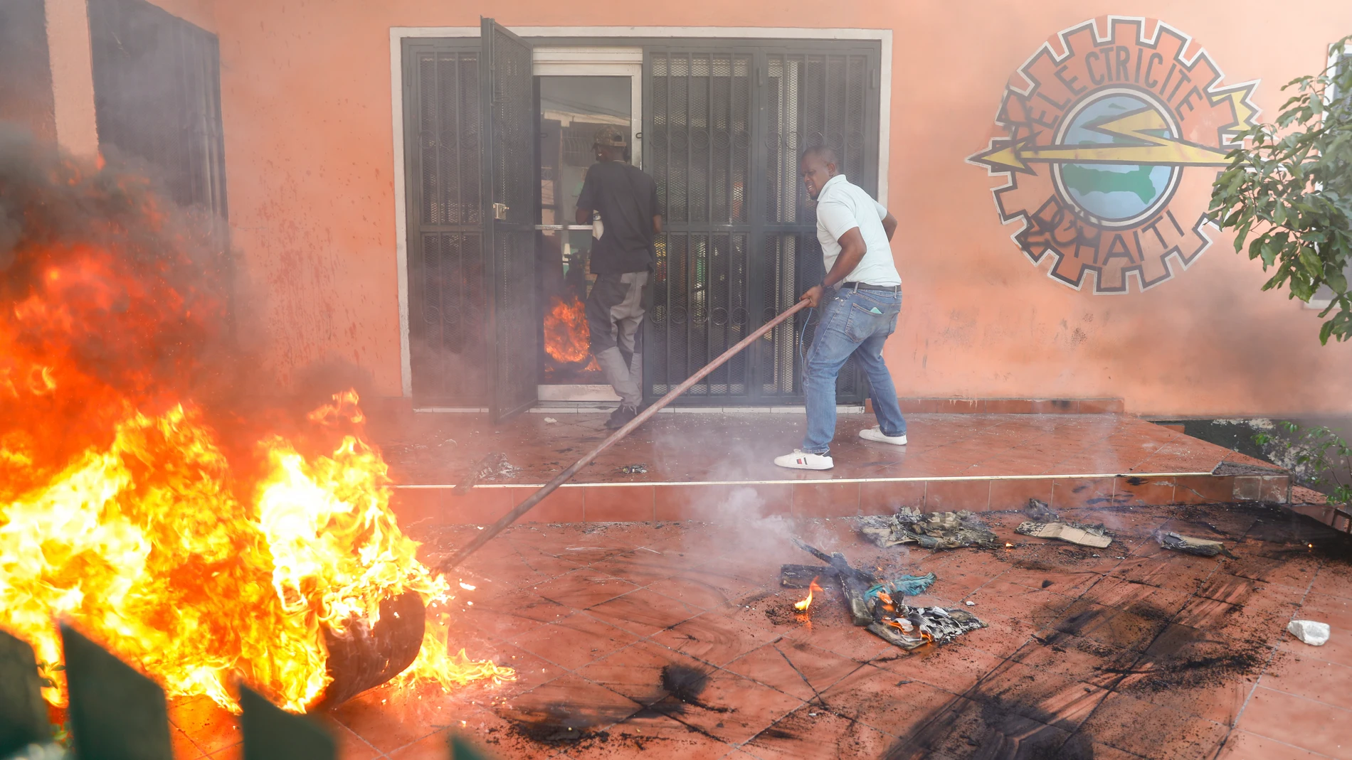 FILE - Workers put down a fire set at an office of Haiti's power company during a protest to demand the resignation of the Prime Minister Ariel Henry in Port-au-Prince, Haiti, Friday, March 1, 2024. Unrelenting gang attacks in Haiti have paralyzed the country and left it with dwindling supplies of basic goods. Worsening the situation is this week's closure of Port-au-Prince's main seaport. The move left stranded scores of containers filled with critical items like food and medical supplies in...