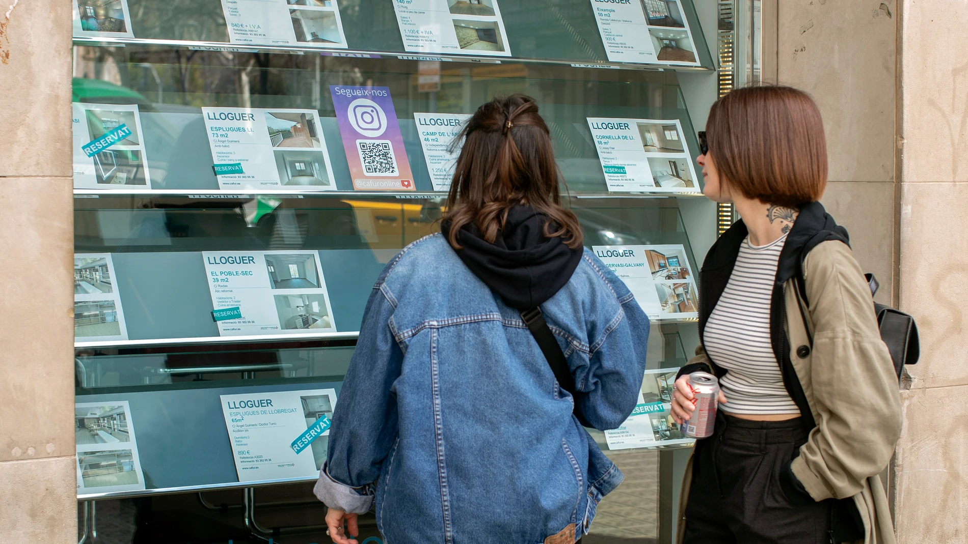 GRAFCAT1202. BARCELONA, 12/03/2024.- Dos personas observan la oferta de pisos en alquiler de una oficina inmobiliaria de Barcelona este martes, a pocos días de que se publique, el próximo viernes, la medida estrella del Gobierno para combatir el alza de los alquileres de viviendas: el índice de precios de referencia, que entrará en vigor de momento sólo en Cataluña, la única comunidad que ha solicitado aplicarlo. EFE/Marta Pérez