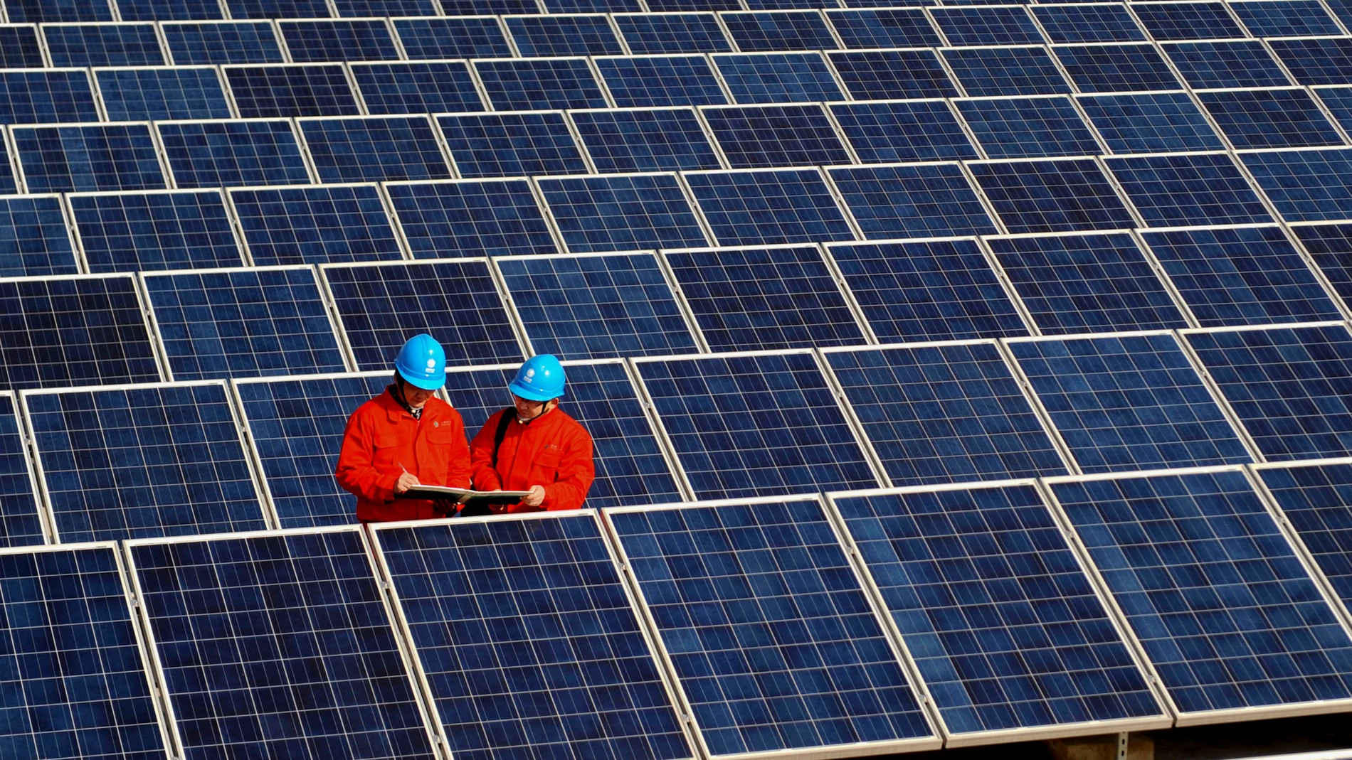 Workers check solar panels at a solar power station on a factory roof in Changxing, eastern China's Zhejiang province.