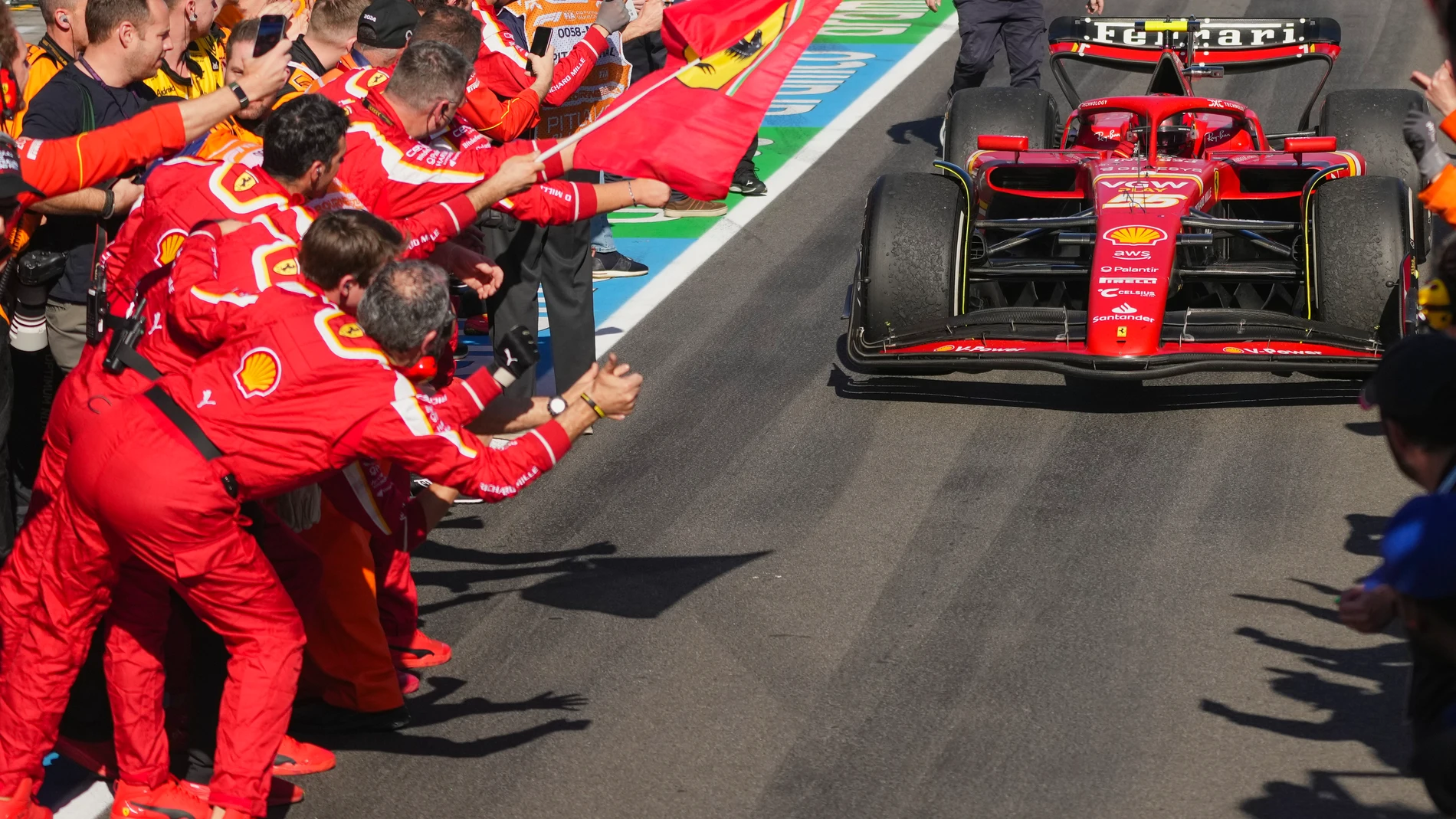 Ferrari driver Carlos Sainz of Spain steers his car into pit lane as his teammates celebrates after winning the Australian Formula One Grand Prix at Albert Park, in Melbourne, Australia, Sunday, March 24, 2024. (AP Photo/Scott Barbour)