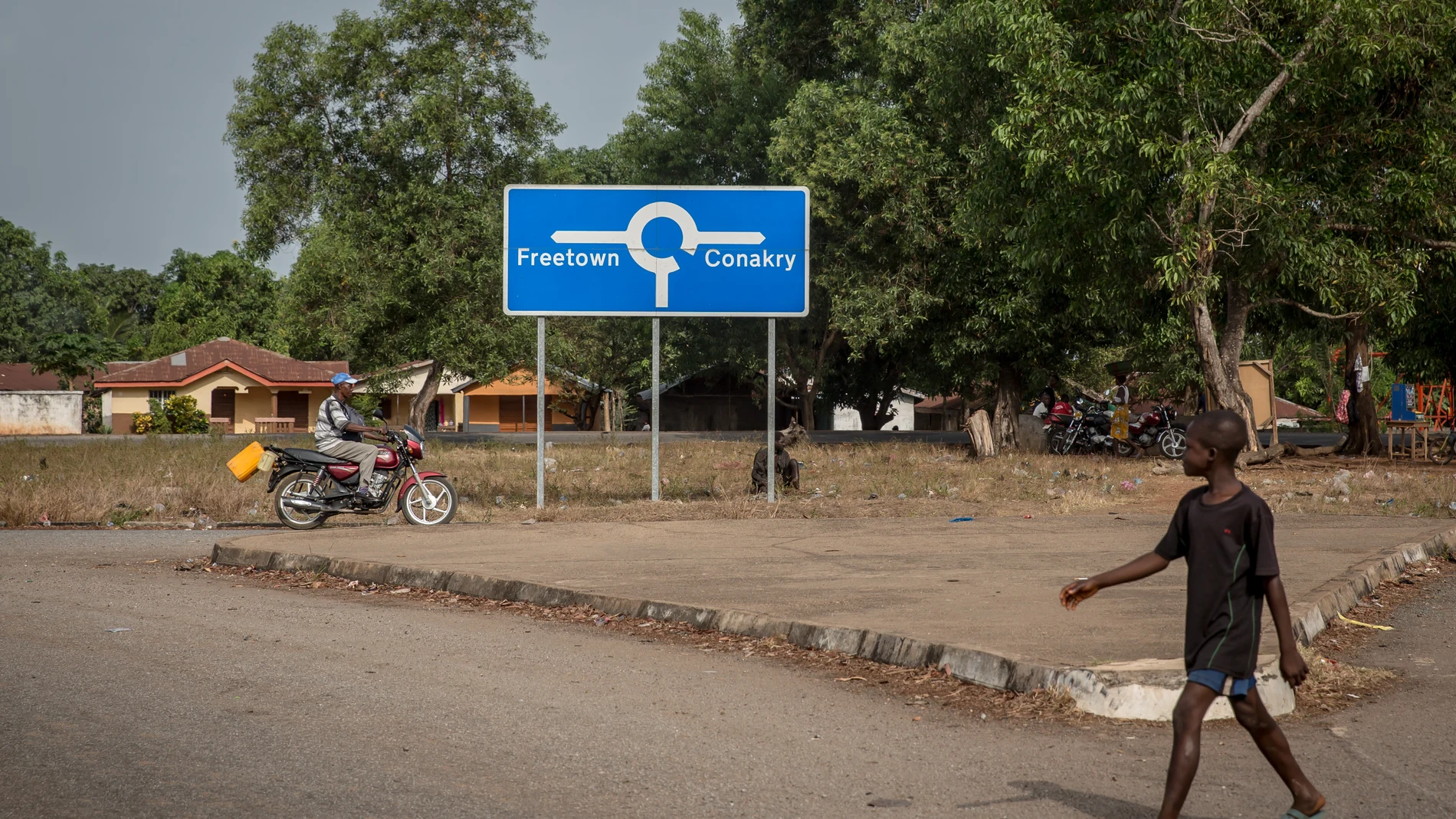 April 1, 2021, Mafaray, Sierra Leone: A boy walks past a signpost that points to both Sierra Leone capital Freetown and Guinea's capital Conakry..The latest Ebola outbreak in Guinea was declared in February 2021. (Foto de ARCHIVO) 01/04/2021