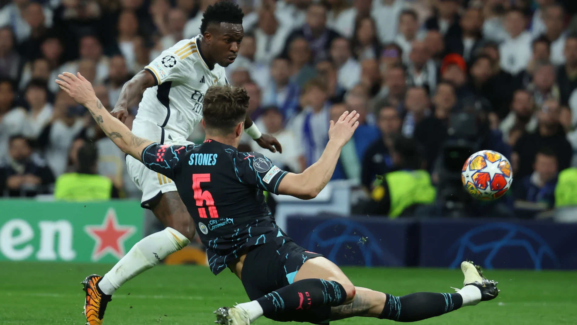 MADRID, 09/04/2024.- El delantero brasileño del Real Madrid, Vinicius Junior (i), golpea el balón ante el defensa del Manchester City, Stones, durante el encuentro correspondiente a los cuartos de final de la Liga de Campeones que Real Madrid y Manchester City disputan hoy martes en el estadio Santiago Bernabéu, en Madrid. EFE / Kiko Huesca.