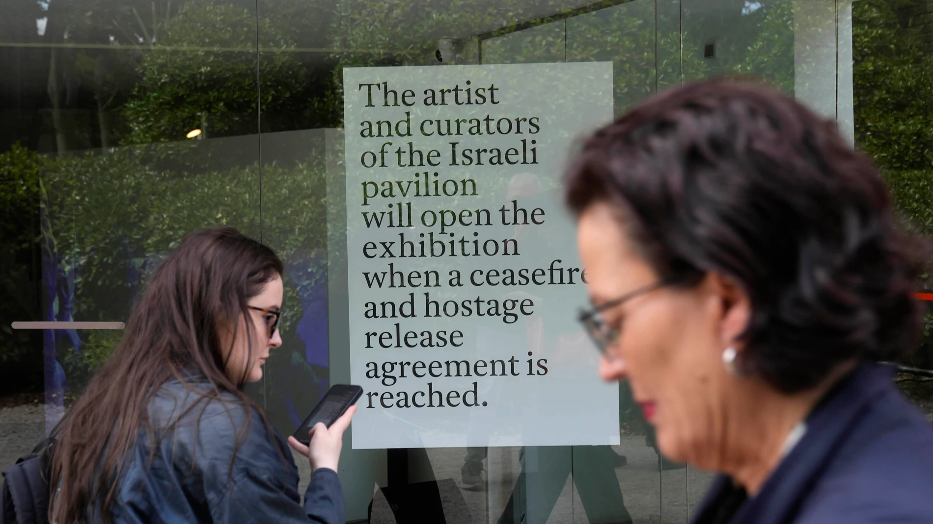 People stand in front of the closed Israeli national pavilion at the Biennale contemporary art fair in Venice, Italy, Tuesday, April 16, 2024. The sign announces that the artist and curators representing Israel at this year's Venice Biennale won't open the Israeli pavilion until there is a cease-fire in Gaza and an agreement to release hostages taken Oct. 7. (AP Photo/Luca Bruno)