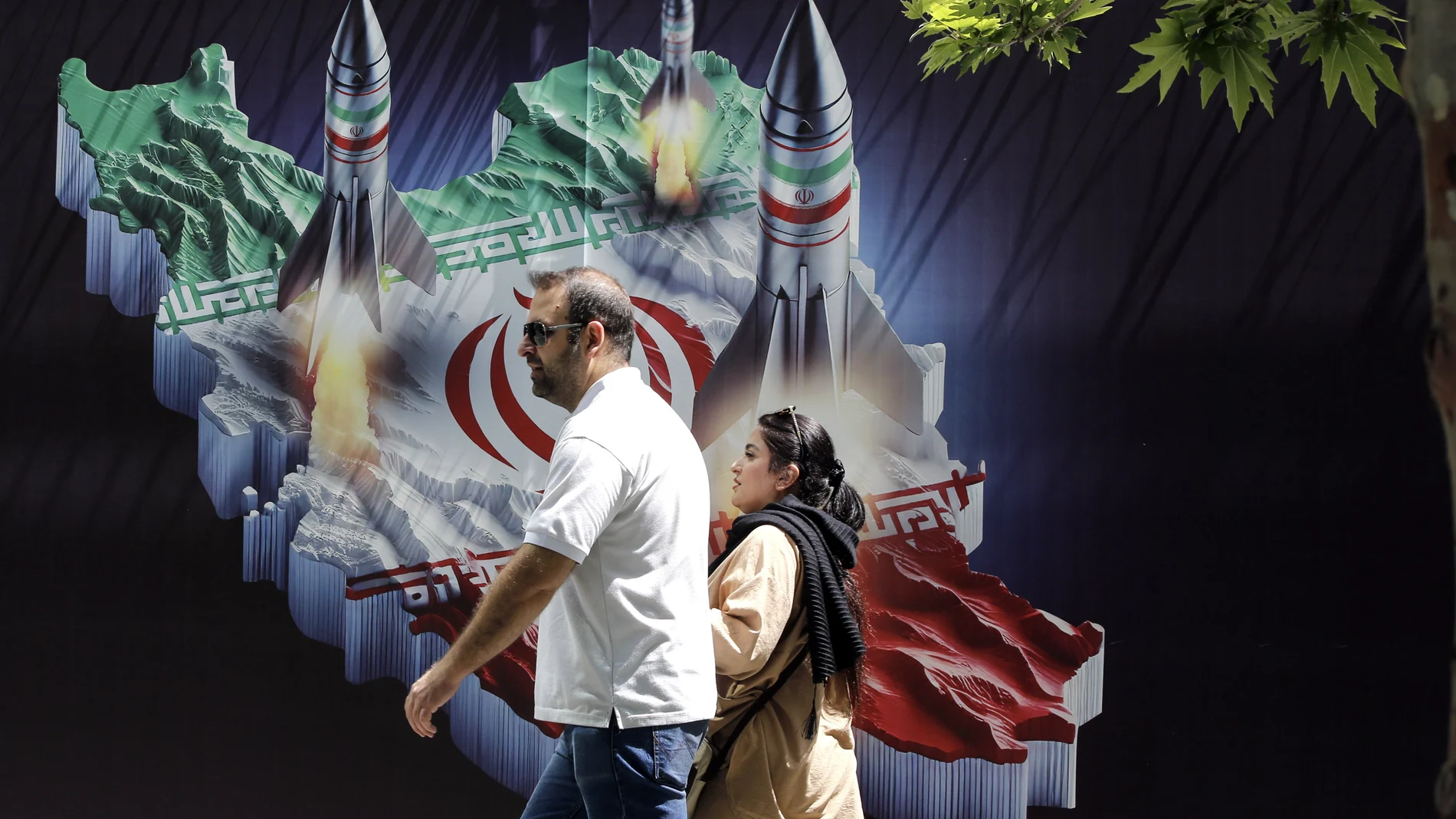 An Iranian couple walk past a huge anti-Israeli banner carrying pictures of missiles on Iran's map, in Tehran, Iran, 19 April 2024. Iranian state media reported that three aerial objects were destroyed by air defense systems over the central city of Isfahan early morning on 19 April.