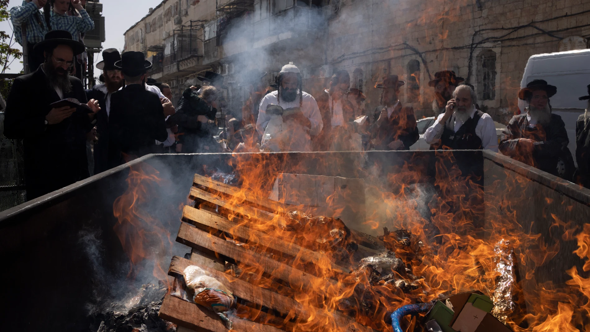 Ultra-Orthodox Jewish men pray next to a container as they burn leavened items in final preparation for the Passover holiday in the Orthodox neighbourhood of Mea Shearim in Jerusalem, Monday, April 22, 2024. Jews are forbidden to eat leavened foodstuffs during the Passover holiday that celebrates the biblical story of the Israelites' escape from slavery and exodus from Egypt. (AP Photo/Leo Correa)