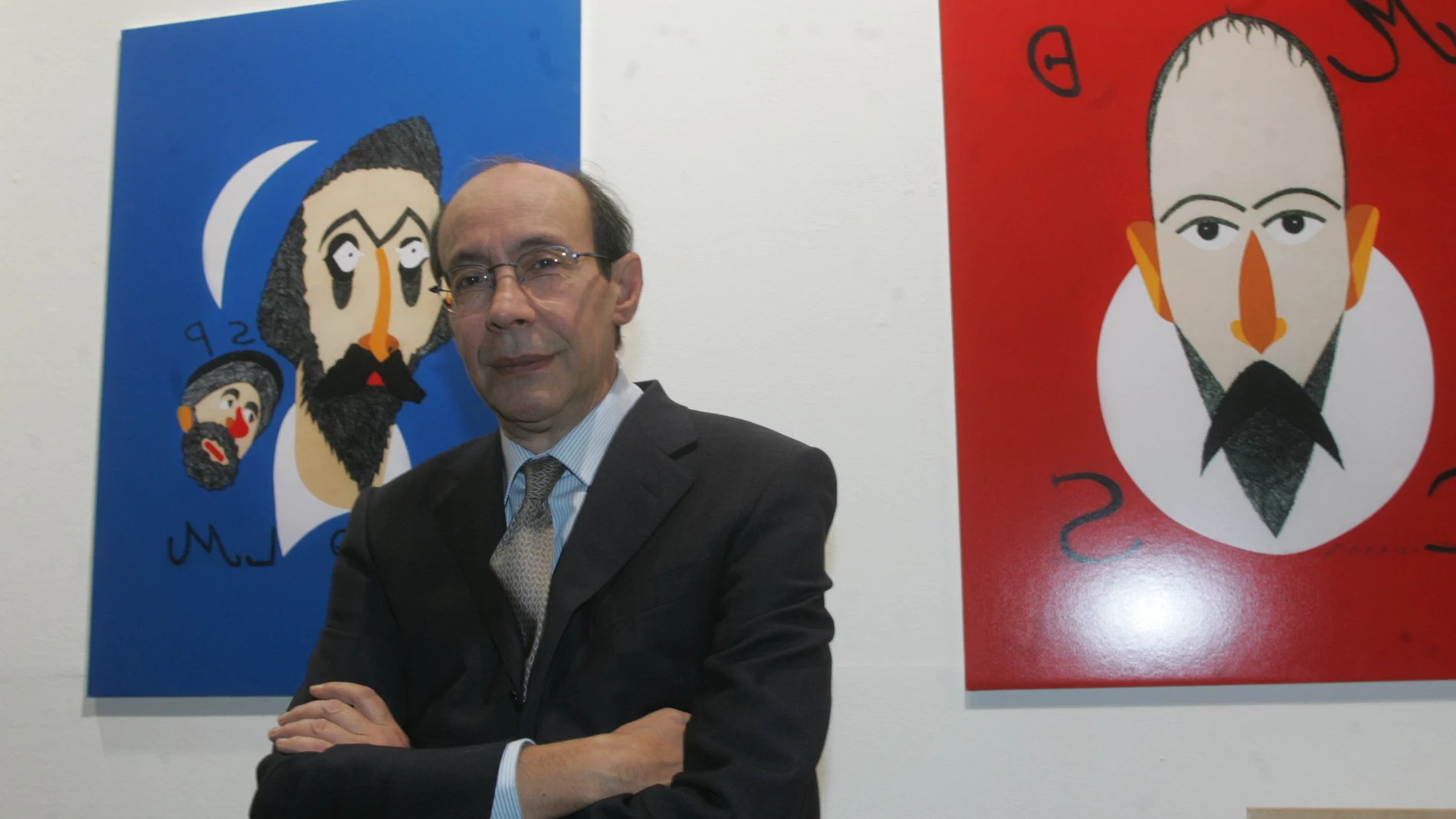Francisco Rico posa delante de unas ilustraciones de Don Quijote, Sancho y Cervantes