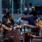 Una mujer le pasa el mechero a otra en una terraza