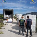 Dos agentes de la Guardia Civil junto a parte del material intervenido