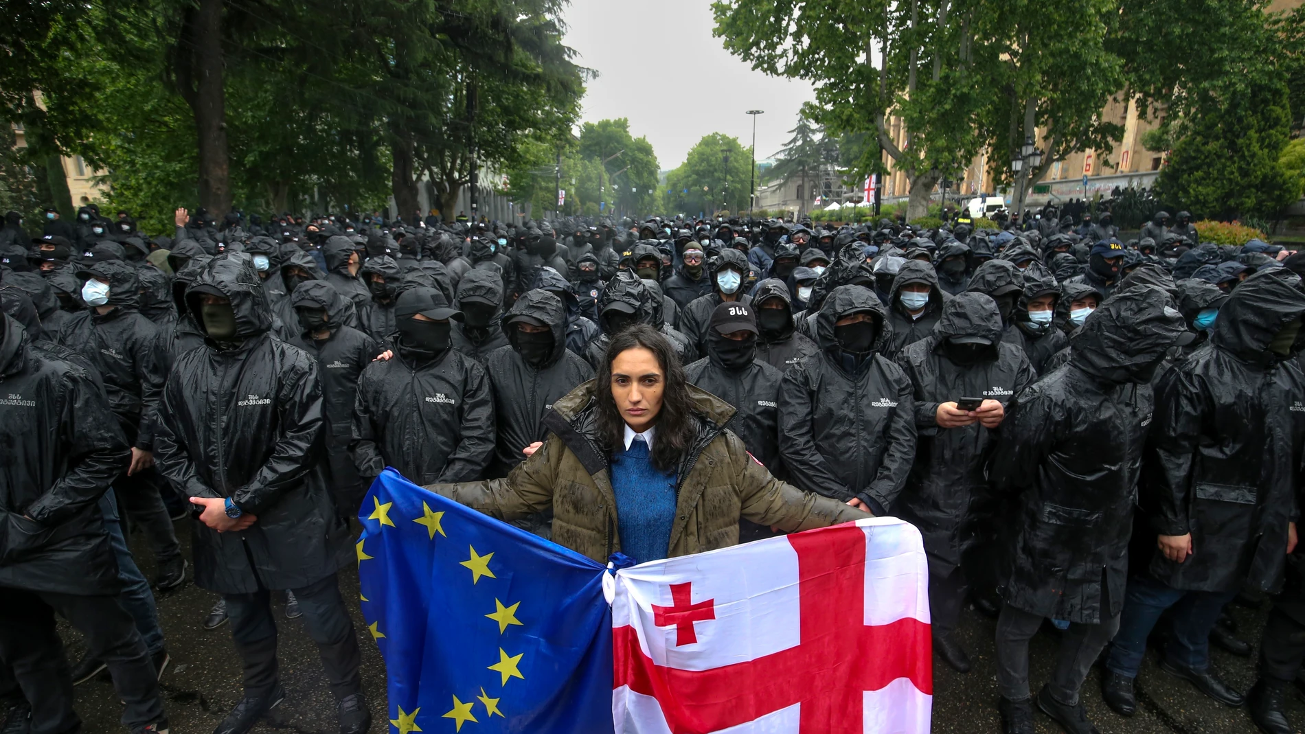 A woman holds a Georgian national and an EU flags in front of riot police blocking a street to prevent demonstrators during an opposition protest against "the Russian law" near the Parliament building in the center of Tbilisi, Georgia, Tuesday, May 14, 2024. The Georgian parliament on Tuesday approved in the third and final reading a divisive bill that sparked weeks of mass protests, with critics seeing it as a threat to democratic freedoms and the country's aspirations to join the European U...