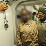 Un militar español traslada a uno de los piratas detenidos