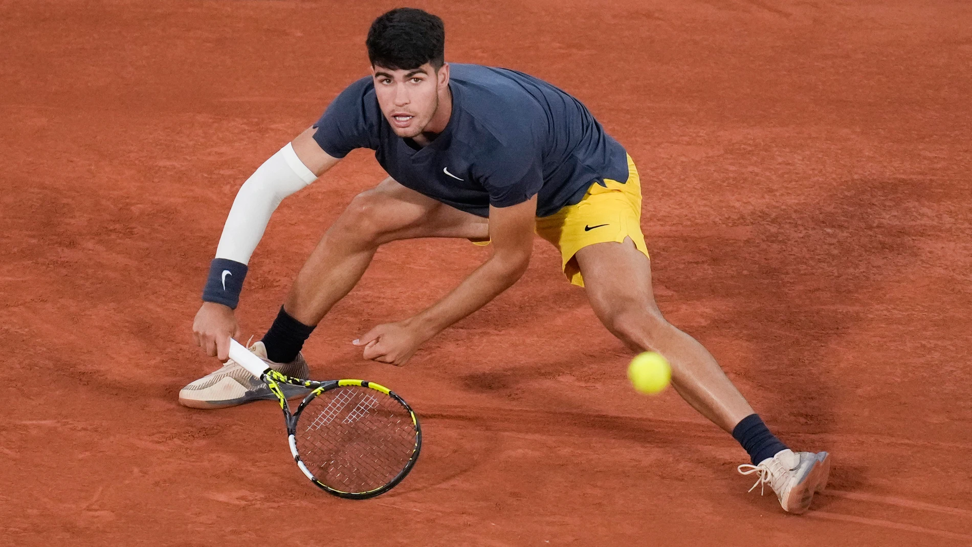 Spain's Carlos Alcaraz slides to play shot against Jeffrey John Wolf of the U.S. during their first round match of the French Open tennis tournament at the Roland Garros stadium in Paris, Sunday, May 26, 2024. (AP Photo/Christophe Ena)