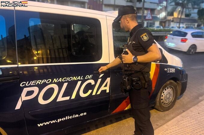 Un agente de la Policía Nacional junto a una furgoneta policial