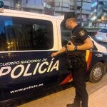 Un agente de la Policía Nacional junto a una furgoneta policial