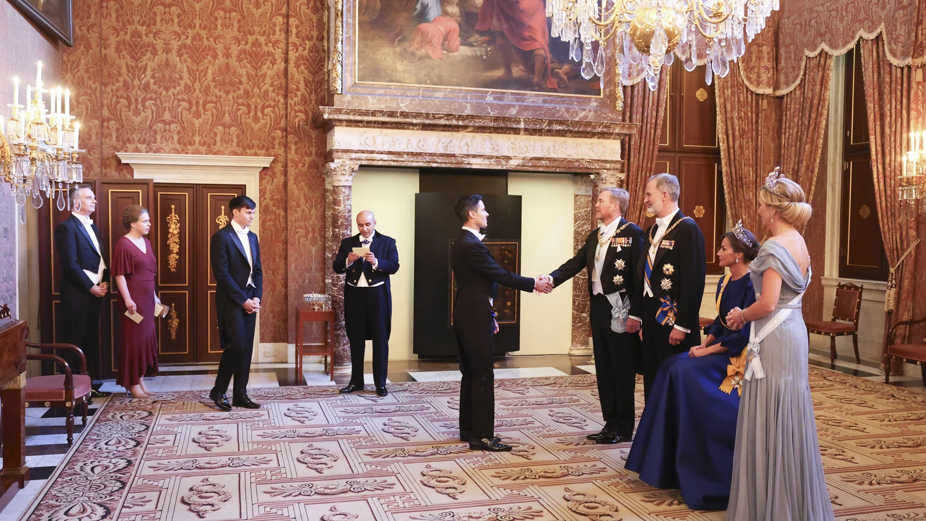 La dolencia que la reina Letizia (2d) sufre en su pie izquierdo, conocida como neuroma de Morton, le ha obligado a protagonizar una imagen insólita al participar sentada en el besamanos previo a la cena de gala ofrecida este miércoles por los reyes de los Países Bajos en el Palacio Real de Ámsterdam.