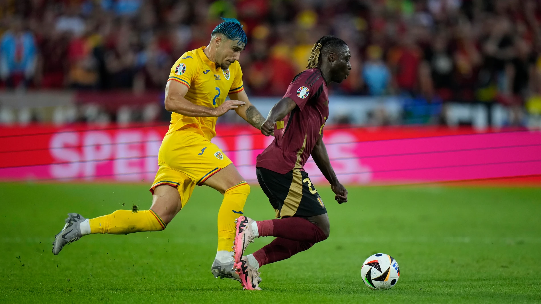 Belgium's Jeremy Doku, right, challenges for the ball with Romania's Andrei Ratiu during a Group E match between Belgium and Romania at the Euro 2024 soccer tournament in Cologne, Germany, Saturday, June 22, 2024. (AP Photo/Alessandra Tarantino)