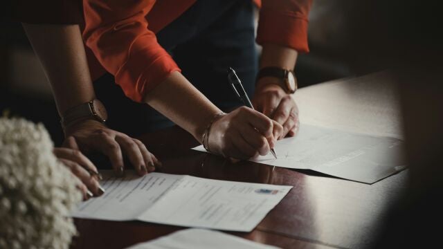 Imagen de una persona firmando unos papeles en una mesa
