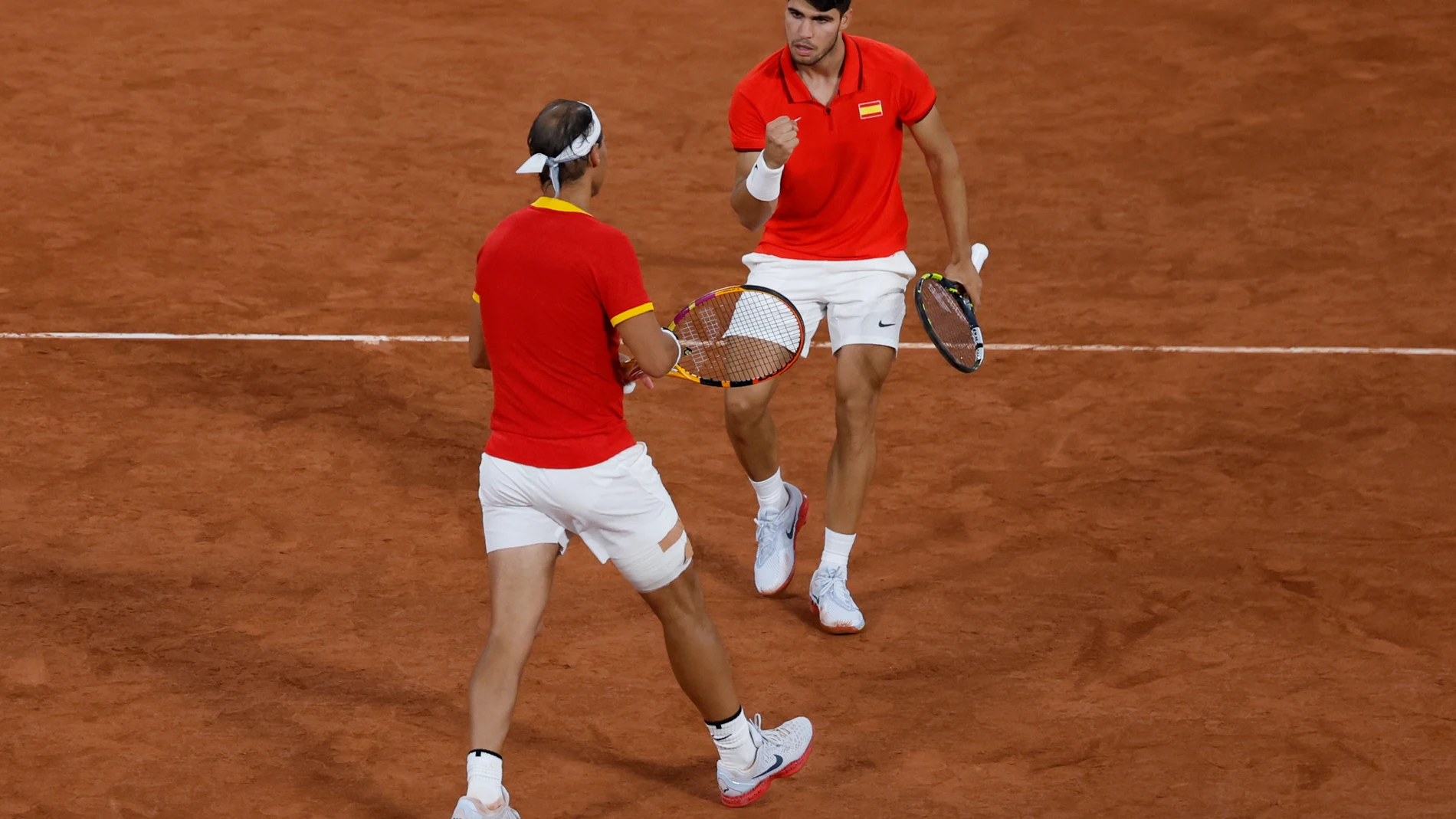 PARÍS, 27/07/2024.- Los tenistas españoles Rafael Nadal (i) y Carlos Alcaraz celebran la victoria en el partido de dobles frente a los argentinos Máximo González y Andrés Molteni, correspondiente a la primera ronda de dobles masculino de tenis de los Juegos Olímpicos de París 2024 este sábado en la pista Phillipe Chatrier de París. EFE/ Juanjo Martín