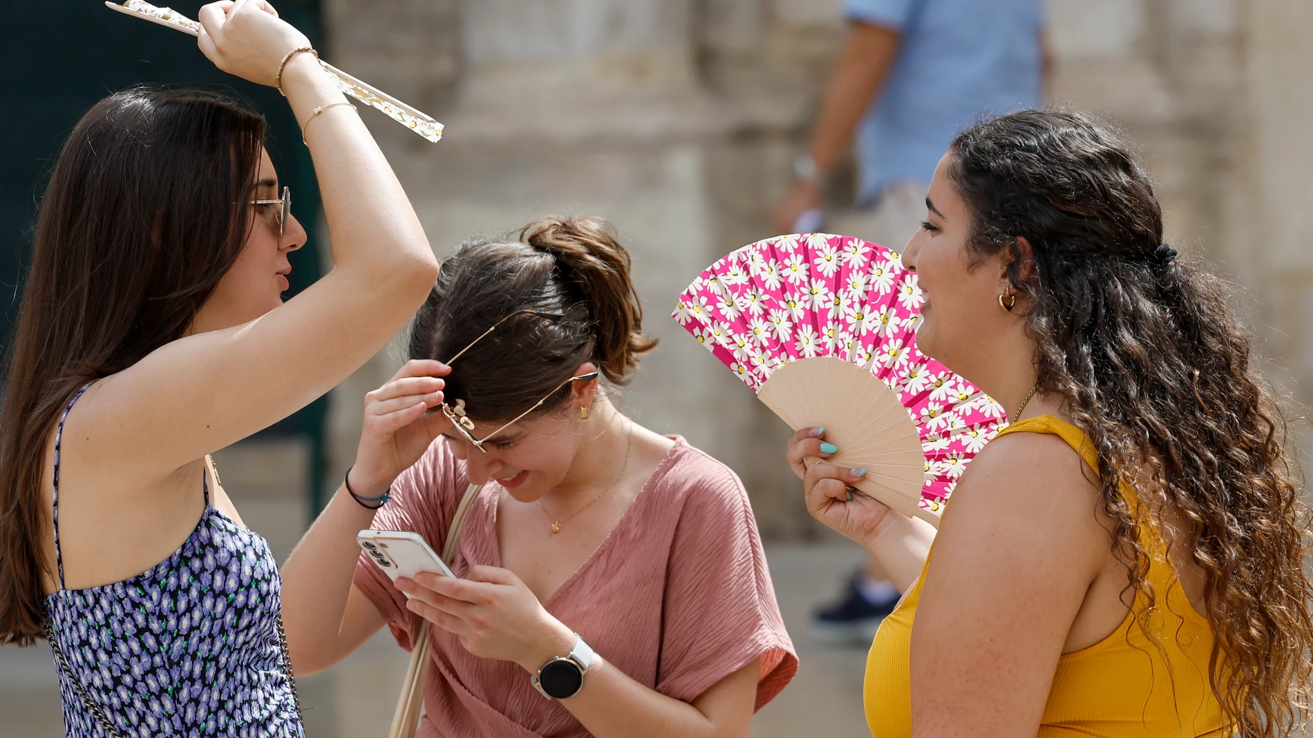 Tres personas se protegen del calor con abanicos