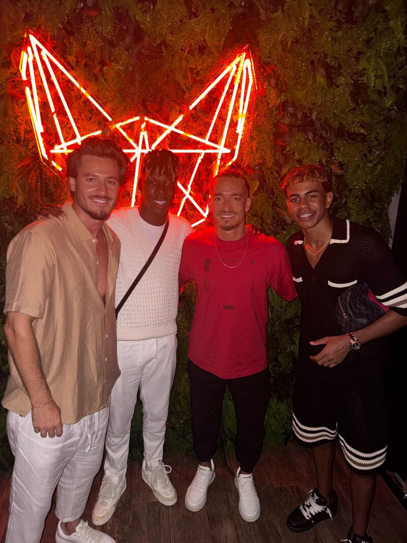 De izquierda a derecha, Roberto Santamaría (socio y cofundador de Grupo Mosh), Nico Williams, Doménico Pastoressa (socio y cofundador de Grupo Mosh) y Lamine Yamal, posando delante del logotipo de Mosh Fun Kitchen