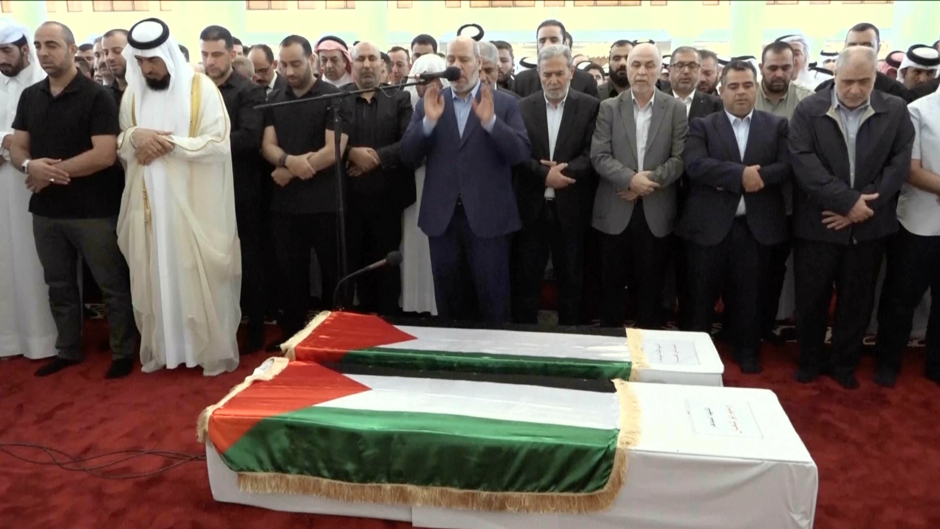 This video grab shows senior Hamas official Khalil al-Hayya, center, praying near the coffin of Hamas leader Ismail Haniyeh and his bodyguard during the funeral prayers in Doha, Qatar, Friday Aug. 2, 2024. (Qatar TV via AP)