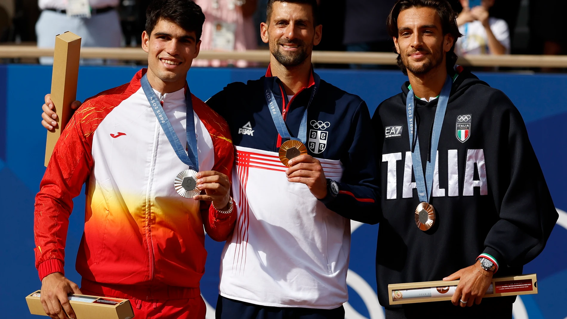 PARIS, 04/08/2024.- Los tenistas, el serbio Novak Djokovic (c-oro), el español Carlos Alcaraz (i-plata) y el italiano Lorenzo Musetti (d-bronce), posan en el podio tras la final individual masculina de tenis de los Juegos Olímpicos de París 2024 este domingo, en la capital gala. EFE/Juanjo Martín