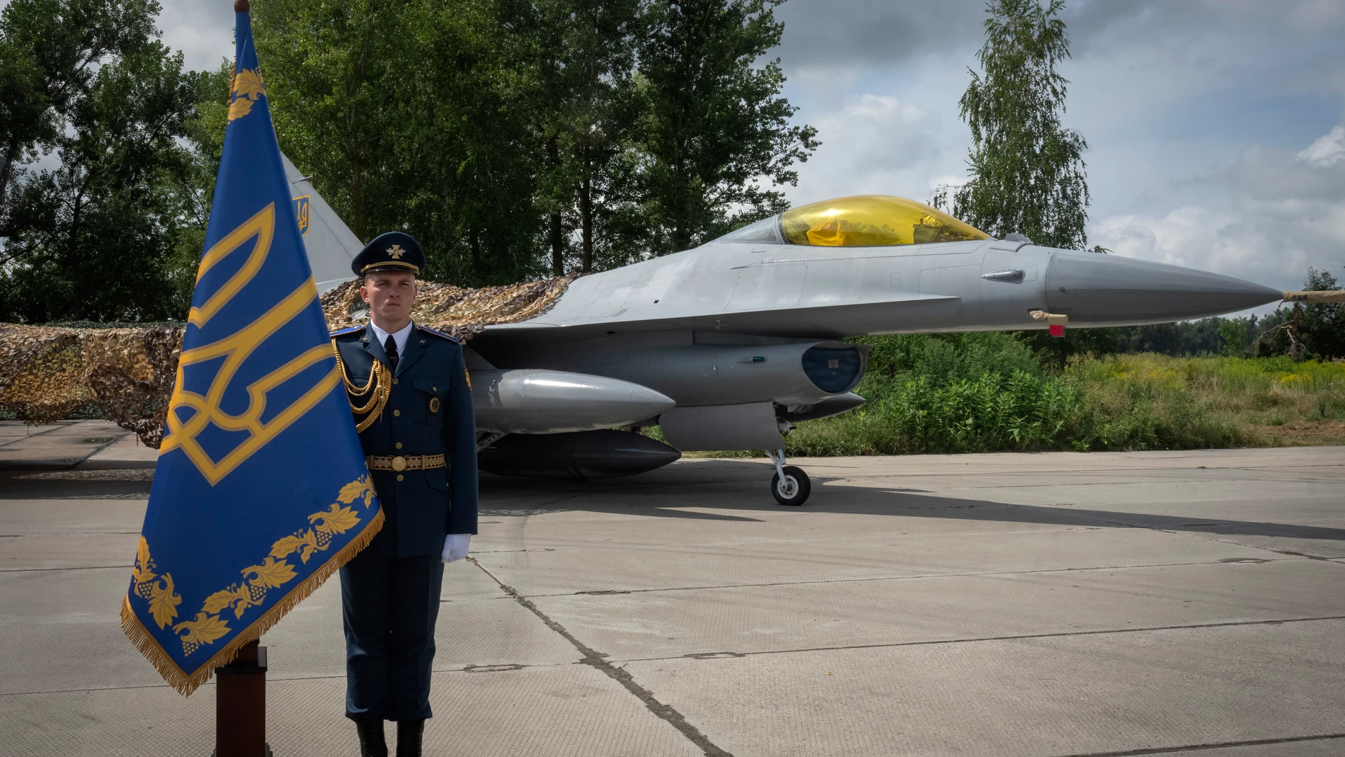 A Ukrainian officer stands in the guard of honour against the background of Ukraine's Air Force's F-16 fighter jets in an undisclosed location in Ukraine, Sunday, Aug. 4, 2024. The F-16 fighter jets that have been delivered to Ukraine by Western countries will be flying sorties in Ukrainian skies and helping the country's current fleet of Soviet-era jets to counter Russia's invasion. (AP Photo/Efrem Lukatsky)