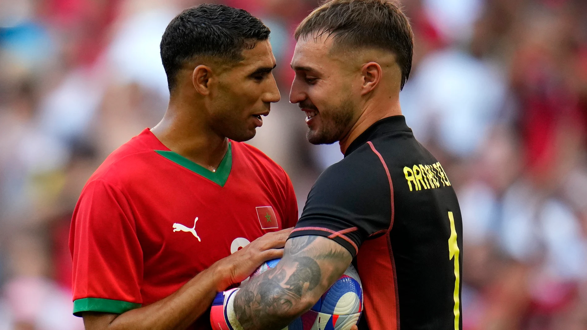 Morocco's Achraf Hakimi speaks with Spain goalkeeper Arnau Tenas during a men's semifinal soccer match between Morocco and Spain at the 2024 Summer Olympics, Monday, Aug. 5, 2024, at Marseille Stadium in Marseille, France. (AP Photo/Julio Cortez)