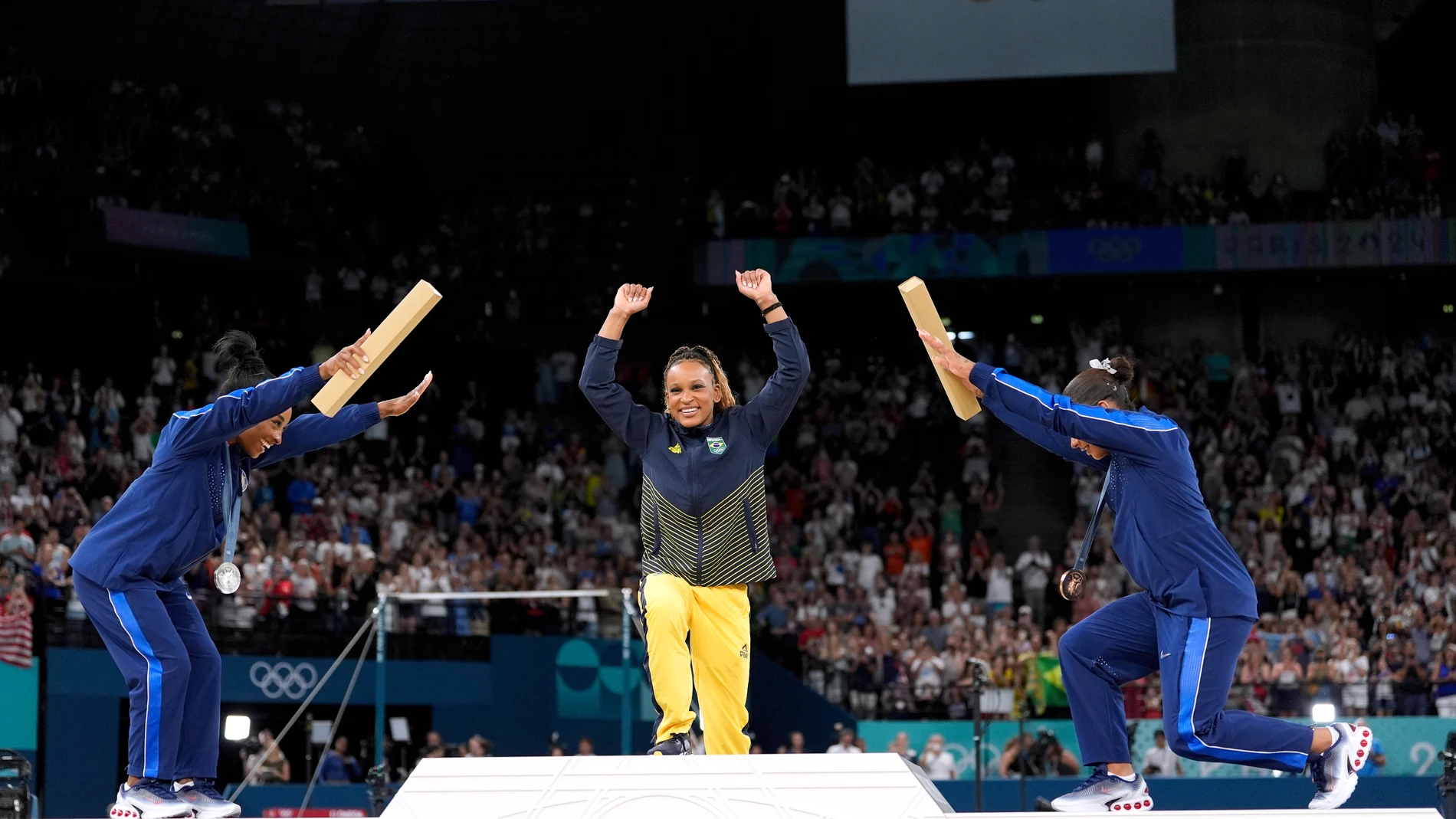Silver medalist Simone Biles, of the United States, left, and bronze medalist Jordan Chiles, of the United States, right, bow to gold medalist Rebeca Andrade, of Brazil, during the medal ceremony for the women's artistic gymnastics individual floor finals at Bercy Arena at the 2024 Summer Olympics, Monday, Aug. 5, 2024, in Paris, France. (AP Photo/Abbie Parr)