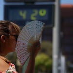  Una mujer se abanica junto a un termómetro de calle que marca 42 grados
