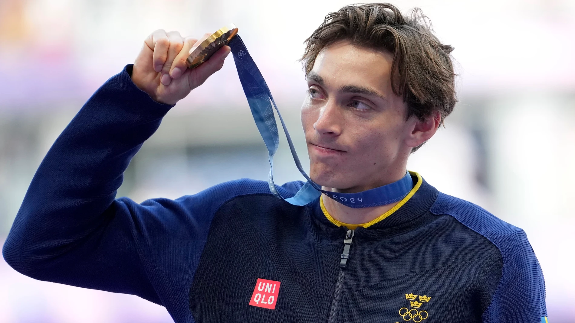 Armand Duplantis, of Sweden, holds up his gold medal while standing on the podium after winning the men's pole vault at the 2024 Summer Olympics, Tuesday, Aug. 6, 2024, in Saint-Denis, France. (AP Photo/Martin Meissner)