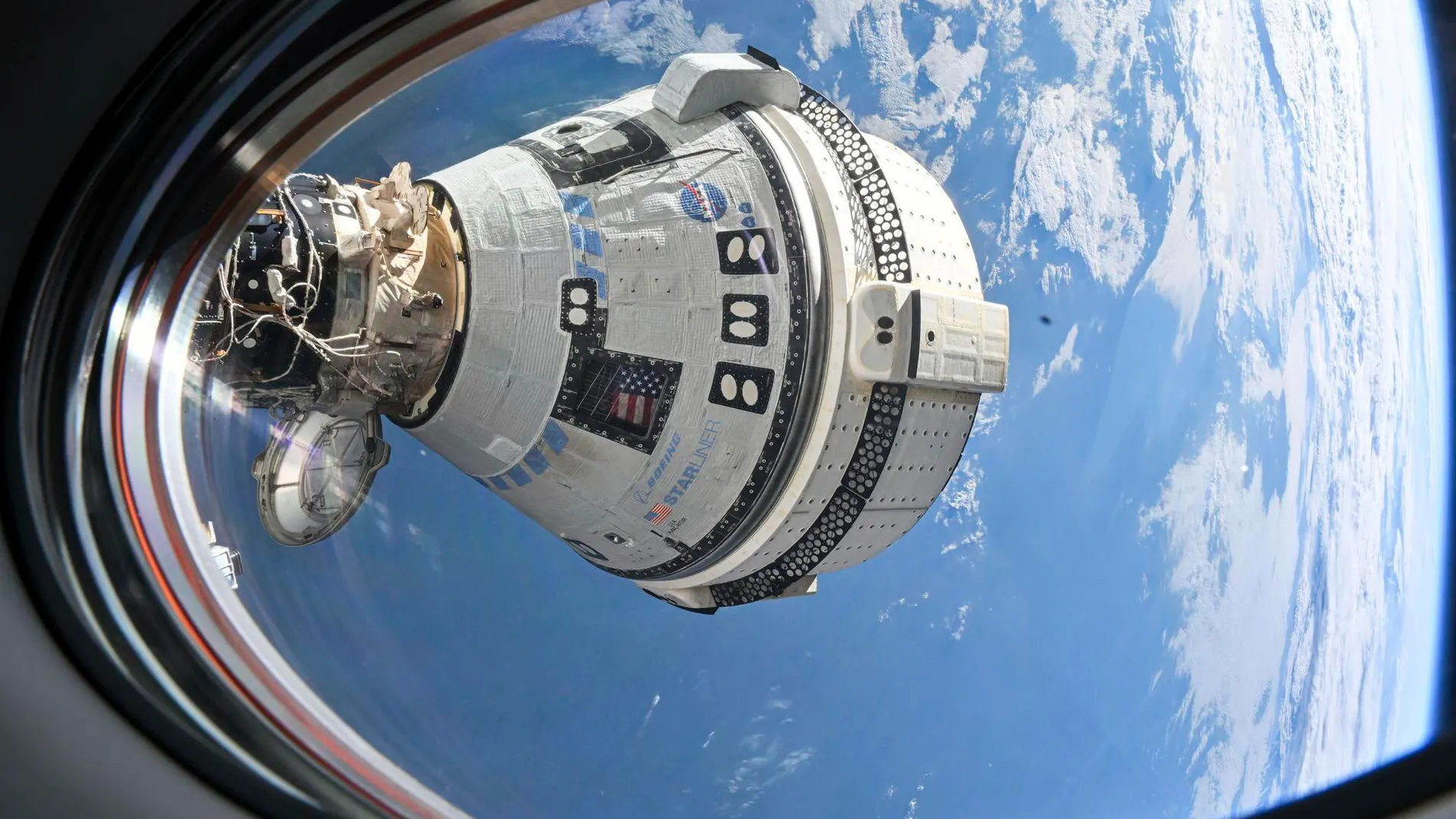 This photo provided by NASA shows Boeing's Starliner spacecraft which launched astronauts Butch Wilmore and Suni Williams to the International Space Station docked to the Harmony module's forward port on July 3, 2024, seen from a window on the SpaceX Dragon Endeavour spacecraft docked to the adjacent port. (NASA via AP)