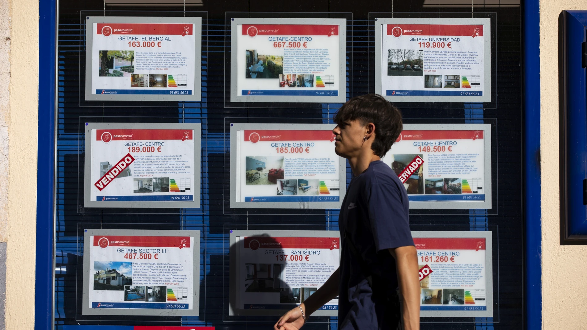 Joven pasando al lado de una inmobiliaria.