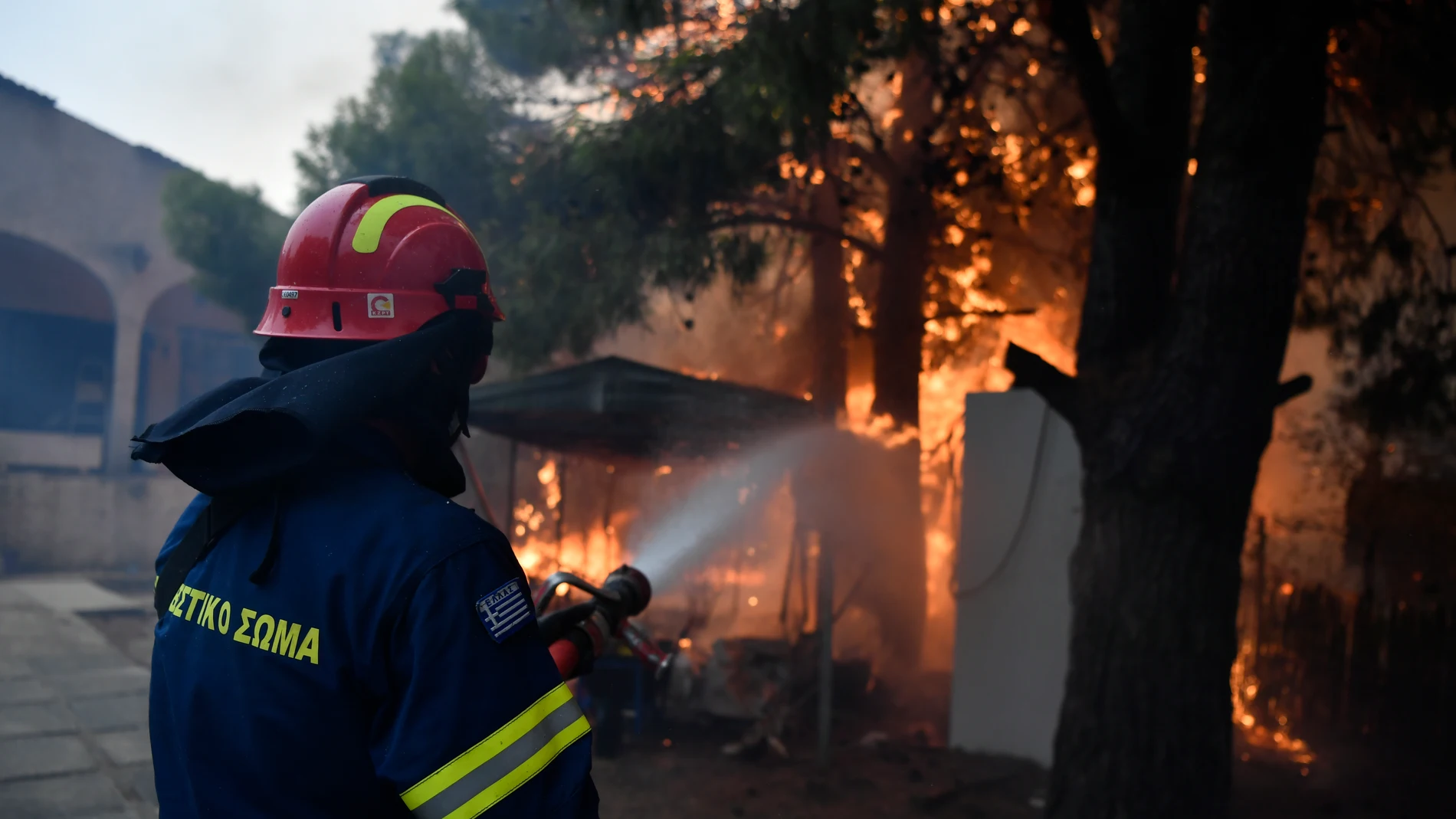 A firefighter works to extinguish the flames at a burning house in northern Athens, Monday, Aug. 12, 2024, as hundreds of firefighters tackle a major wildfire raging out of control on fringes of Greek capital. (AP Photo/Michael Varaklas)