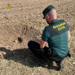 Agente de la Guardia Civil junto al proyectil de artillería hallado por un agricultor en Guadalajara