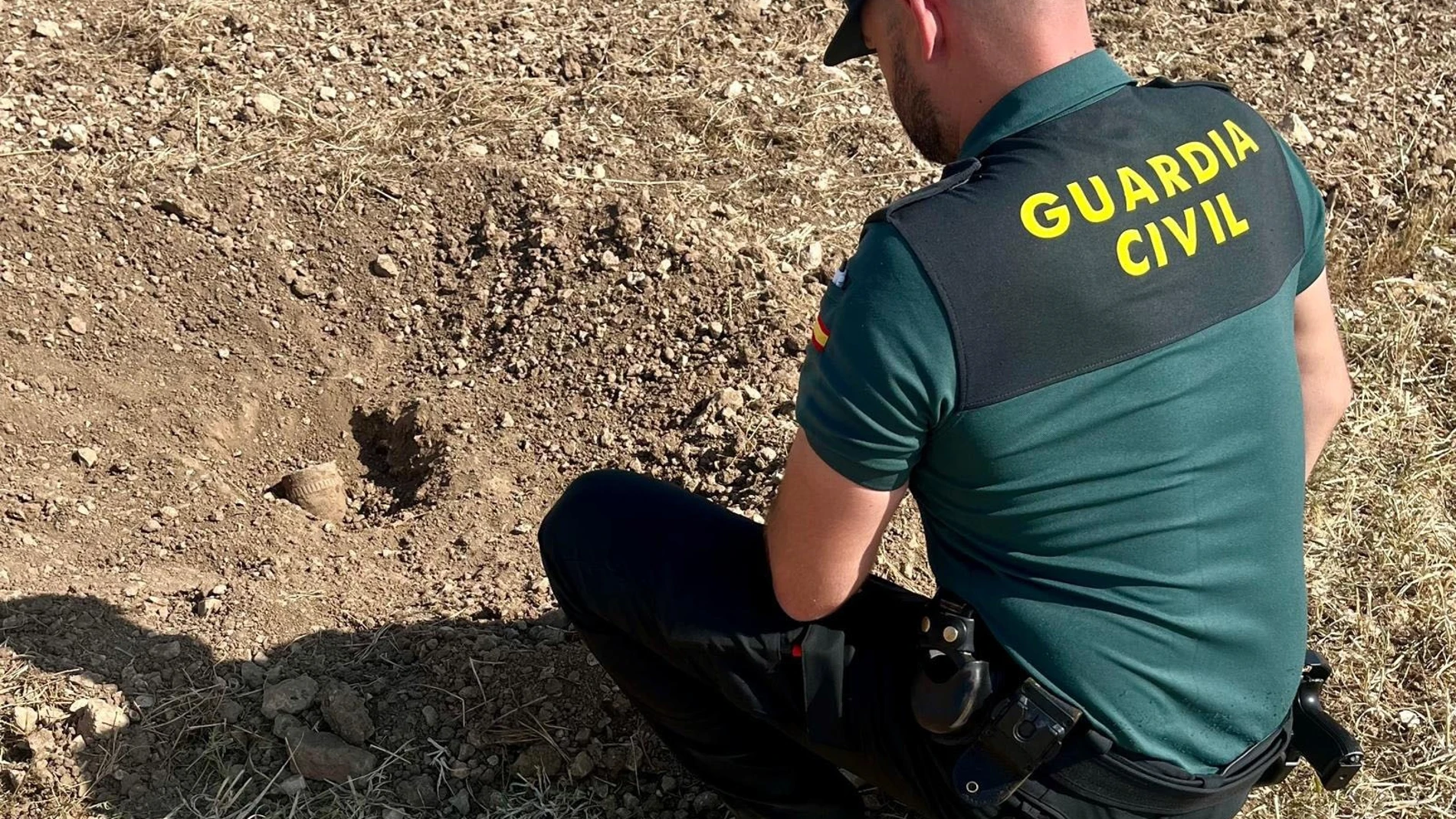 Agente de la Guardia Civil junto al proyectil de artillería hallado por un agricultor en Guadalajara