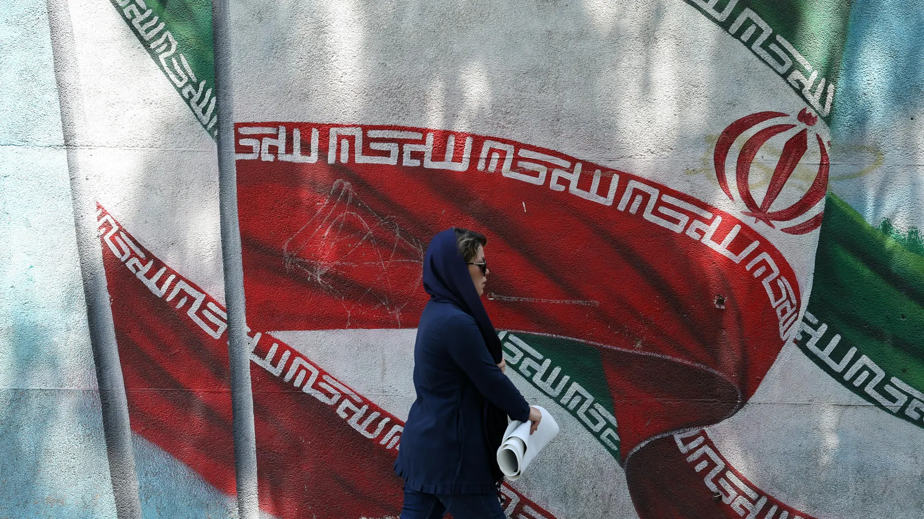 Tehran (Iran(islamic Republic Of)), 13/08/2024.- An Iranian woman walks past next to a wall painting of Iran's national flag on a street in Tehran, Iran, 13 August 2024. Tension remains high between Iran and Israel since late Hamas leader Ismail Haniyeh was killed in Tehran on 31 July 2024, as Iran's leader Ayatollah Khamenei had vowed for a 'harsh punishment' against Israel in retaliation over the killing of Haniyeh. US and EU administration asked Iran not to attack Israel. (Teherán) EFE/EPA...