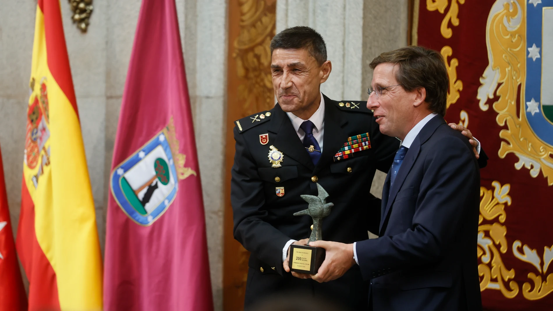 MADRID, 15/08/2024.- El alcalde de Madrid, Jose Luis Martinez-Almeida (d), entrega una insignia al Policía Nacional, Manuel Soto (i), durante el acto de entrega de "Las Palomas de Bronce-Bomberos de Madrid" con motivo de la Virgen de la Paloma, patrona del cuerpo de Bomberos de la capital, este jueves en el Ayuntamiento de Madrid. EFE/ Fernando Alvarado