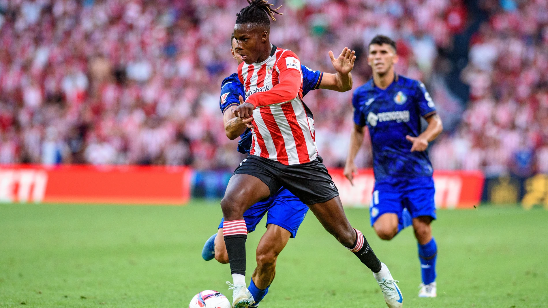 BILBAO, 15/08/2024.- El delantero del Athletic Club de Bilbao Nico Williams (d) conduce un balón ante el defensa del Getafe CF Juan Iglesias (i), durante el partido de Liga en Primera División que disputan este jueves en el estadio de San Mamés, en Bilbao. EFE/Javier Zorrilla