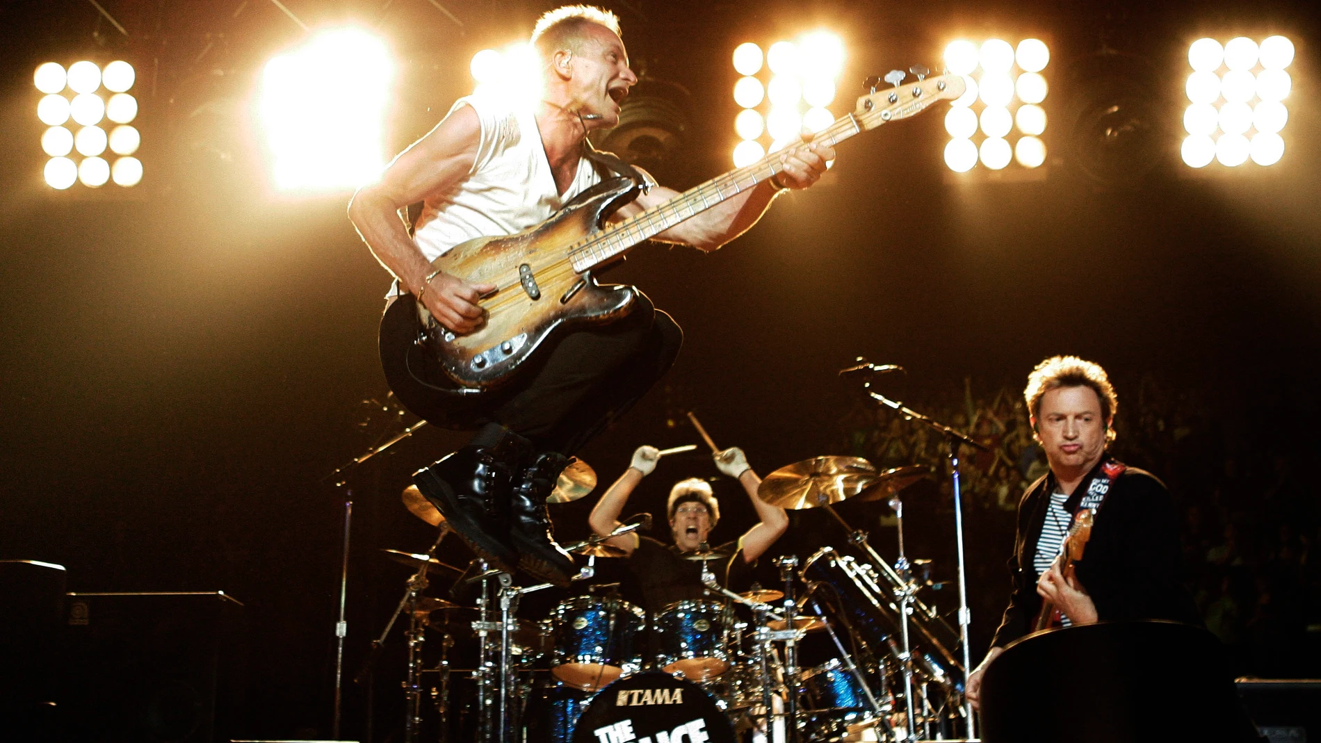 Sting, left, bassist and lead singer of the rock band, The Police, leaps in the air as he performs with Andy Summers, guitarist, and drummer Stewart Copeland, founding member of the band, at the Staples Center in Los Angeles