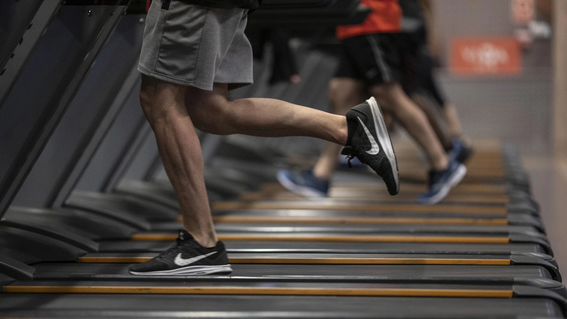 Gente corriendo en la cinta de un gimnasio.