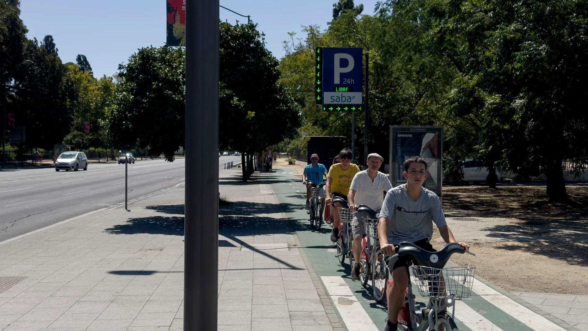 SEVILLA, 17/08/2024.- Un grupo de personas pasea en bicicleta por una calle de Sevilla donde la Agencia Estatal de Meteorología (Aemet) ha declarado la alerta naranja por altas temperaturas. EFE/David Arjona