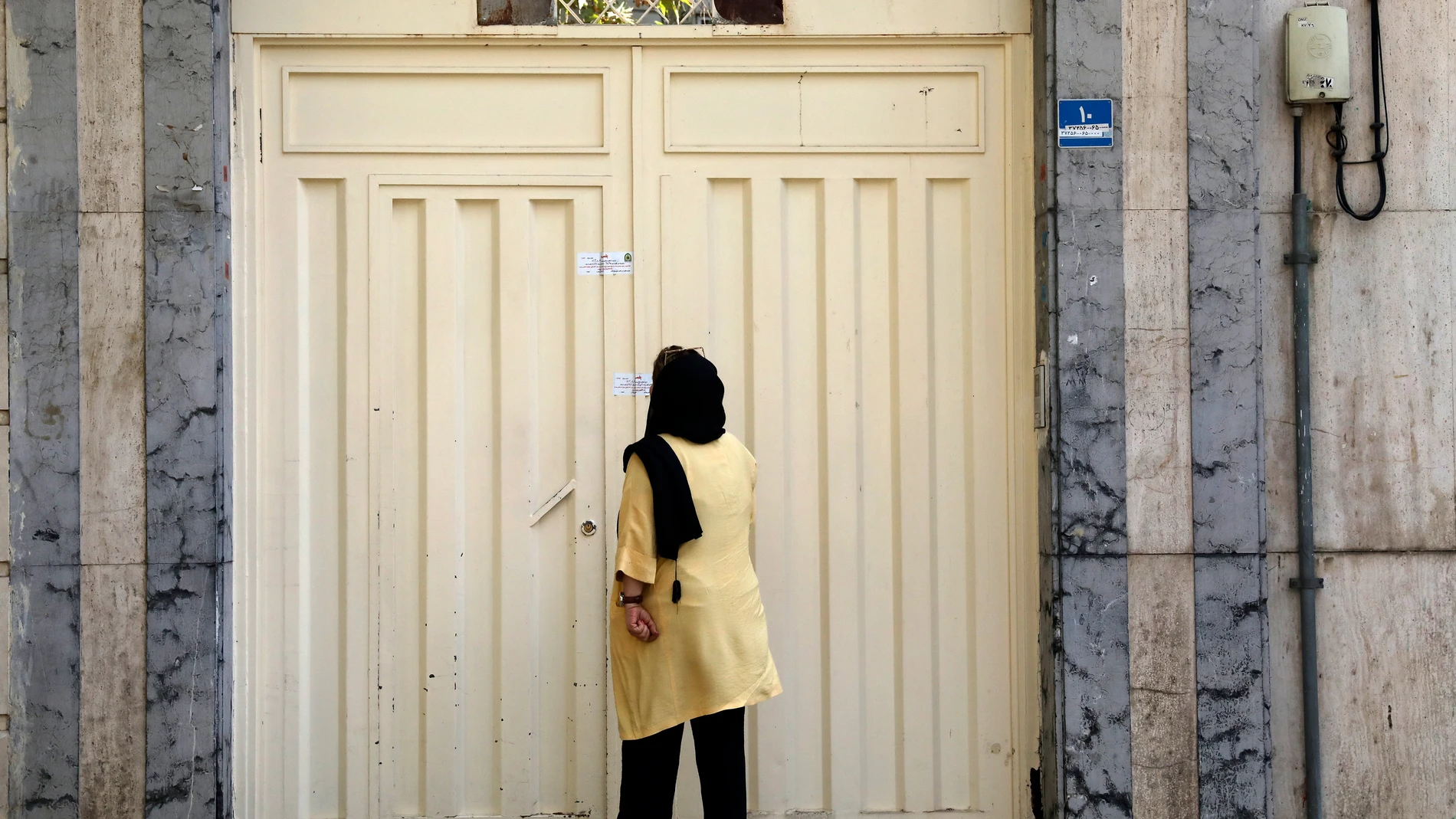 A woman reads the Iranian police closure notice on the gate of a language institute certified by the German embassy, in northern Tehran, Iran, Tuesday, Aug. 20, 2024. (AP Photo/Vahid Salemi)