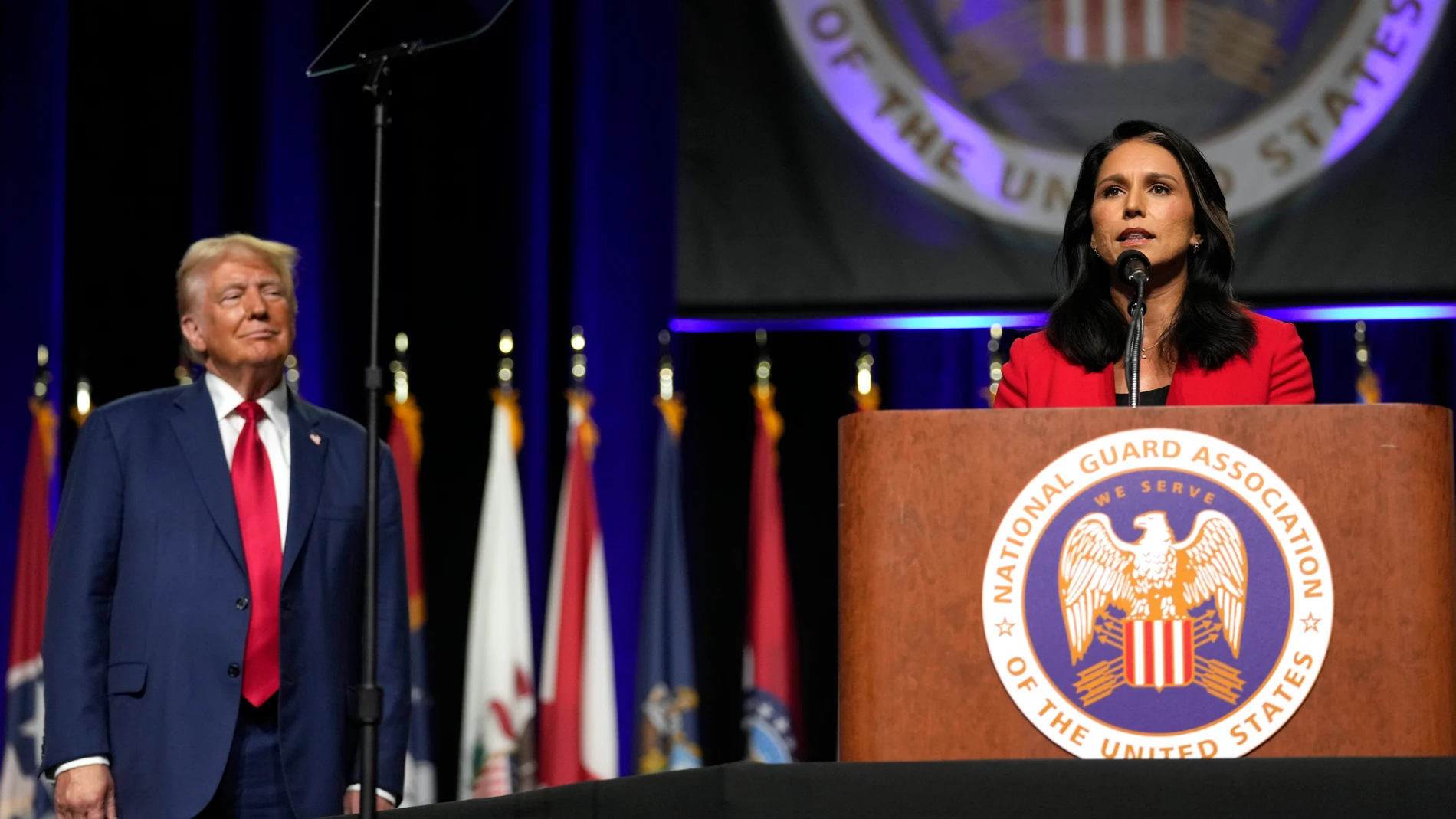 Republican presidential nominee former President Donald Trump, left, looks on as former Rep. Tulsi Gabbard of Hawaii, speaks at the National Guard Association of the United States' 146th General Conference, Monday, Aug. 26, 2024, in Detroit. (AP Photo/Carolyn Kaster)