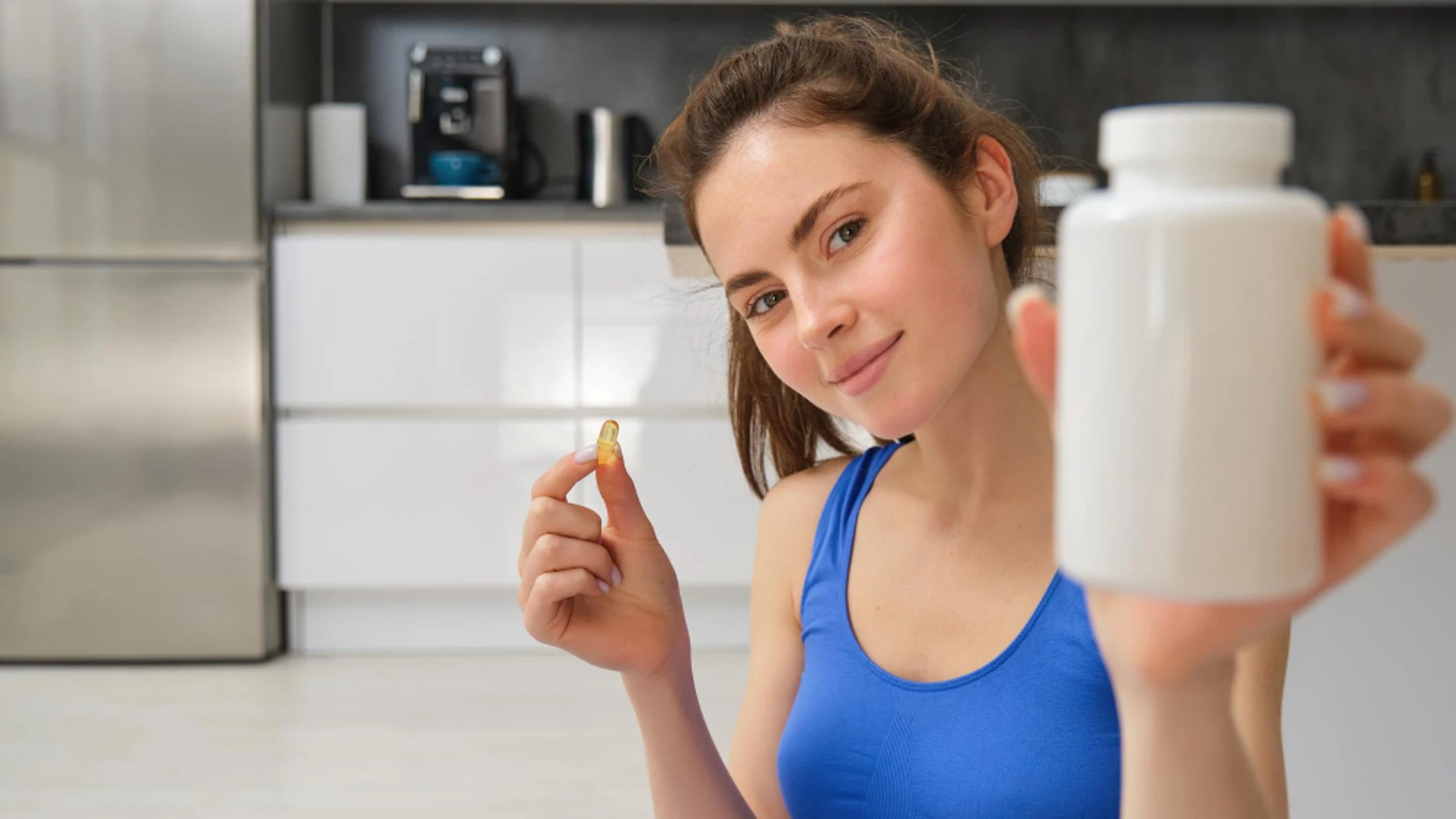 Una chica sostiene un bote de suplementos nutricionales